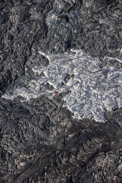 The active flows seen from above look like patches of metallic silver on the black, cooled lava.